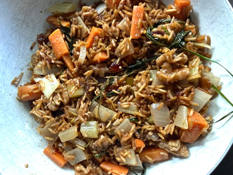 A bowl of autumn harvest risotto: brown basmati rice with carrots, onion, dried cranberries, walnuts, and fresh herbs.